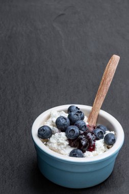 Böğürtlen reçelli süzme peynir ve siyah taş arka planda seramik kase 