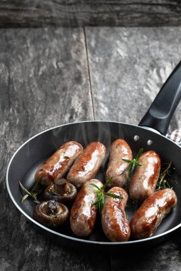 Kırsal ahşap masada kızarmış tavada leziz domuz sosisi. 