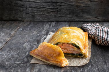 Ev yapımı somon Wellington, ıspanak ve mantarlı, ahşap masa. 