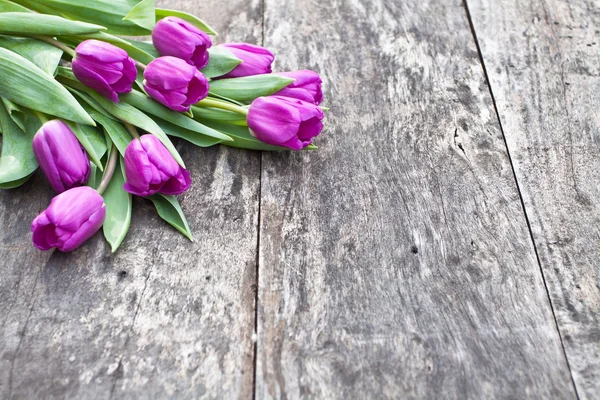 Bouquet of violet tulips on the oak brown table — Stock Photo, Image