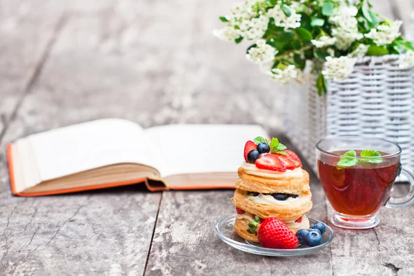 Puff pastry with berries old book and beautiful bouquet of white — Stock Photo, Image