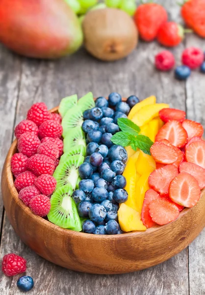 Frutas e bagas coloridas frescas em tigela de madeira na mesa rústica — Fotografia de Stock