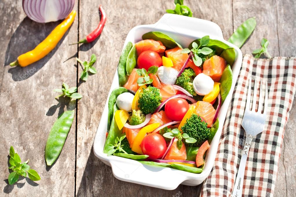 Tasty fried and grilled salmon slices on mixed colorful vegetabl