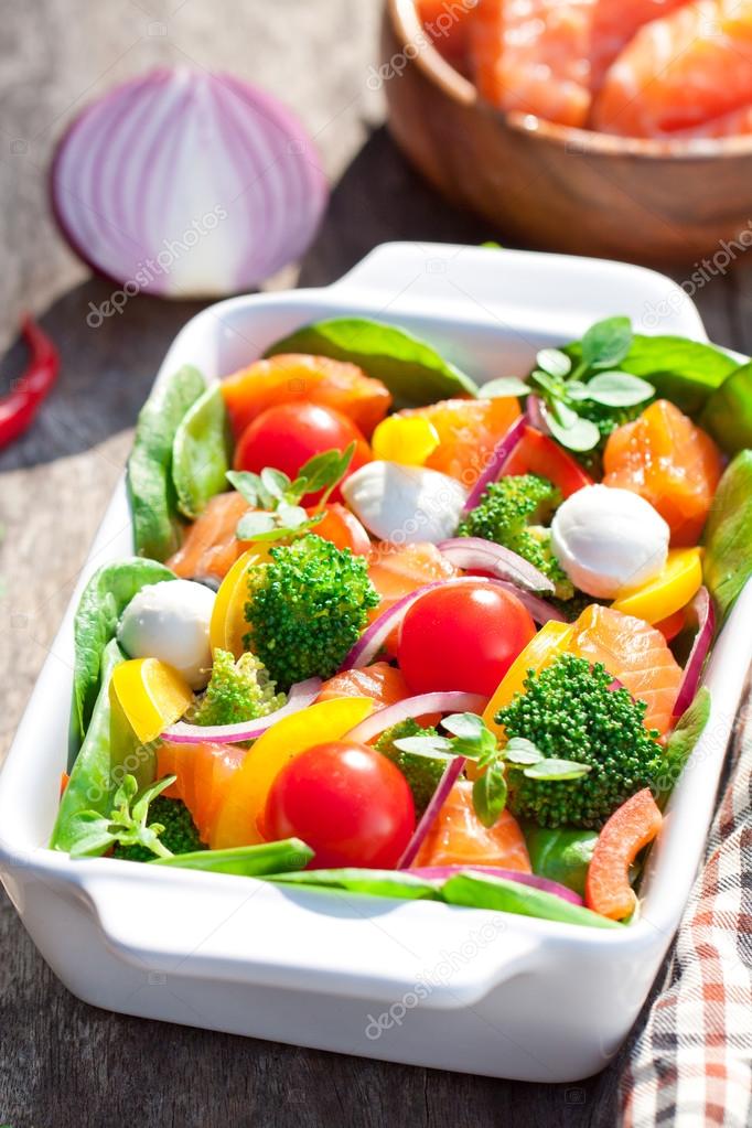 Tasty fried and grilled salmon slices on mixed colorful vegetabl