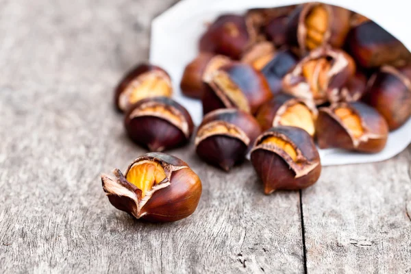 Castanhas assadas em fundo de madeira — Fotografia de Stock