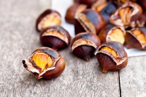 Castanhas assadas em fundo de madeira — Fotografia de Stock