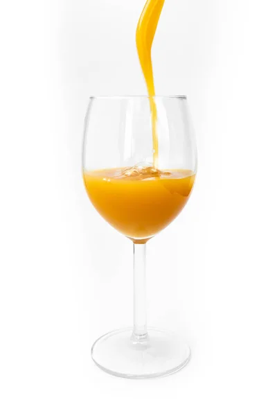 Suco de laranja fresco é derramado em um copo em um fundo branco — Fotografia de Stock