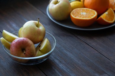Elmalar bir tabakta diğer meyvelerin yanında siyah tahta bir masada.