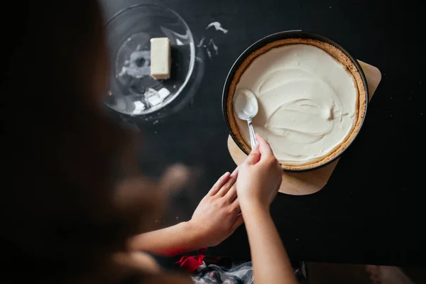 Hermosa chica pone comida en un plato para hornear en la cocina — Foto de Stock