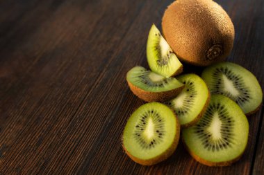 kivi ve doğranmış kivi parçaları koyu ahşap arka planda