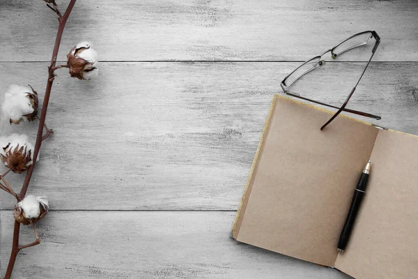 Ambachtelijke notebook met pen, bril, katoenen tak op een lichte houten achtergrond — Stockfoto