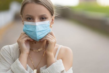 Kız sokakta tıbbi maske takıyor.