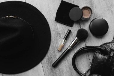 Şapka, fırça, makyaj çantası ve arkaplanda pudra.