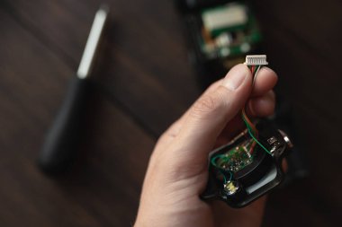 Bir adam elinde bir elektrikli aletin bir parçasını tutuyor ve bir bağlantı döngüsü gösteriyor