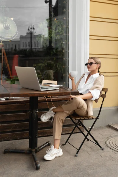 Mooi meisje in een straat cafe drinkt koffie — Stockfoto