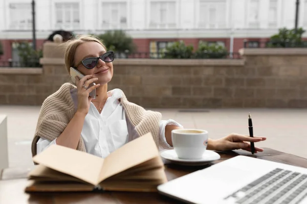 Красивая девушка в уличном кафе разговаривает по телефону — стоковое фото