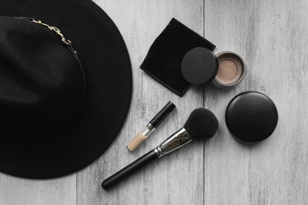 Topi, kuas makeup dan bubuk pada latar belakang kayu ringan — Stok Foto