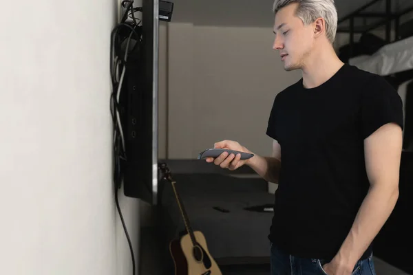 Bir adam evde televizyon kurmakla meşgul.