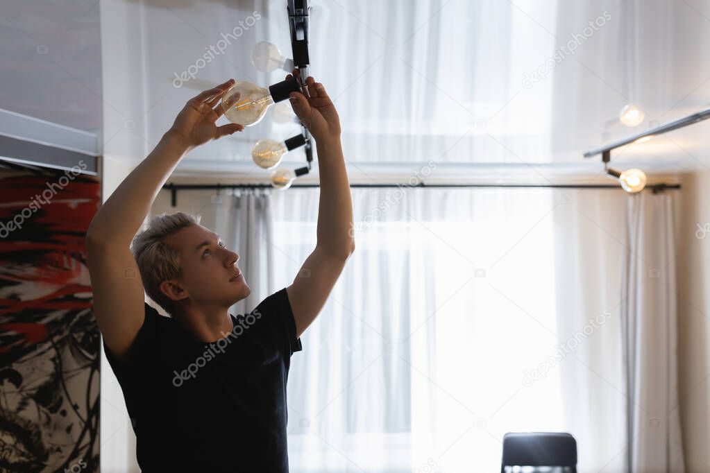 A man with white hair changes a burnt out light bulb at home