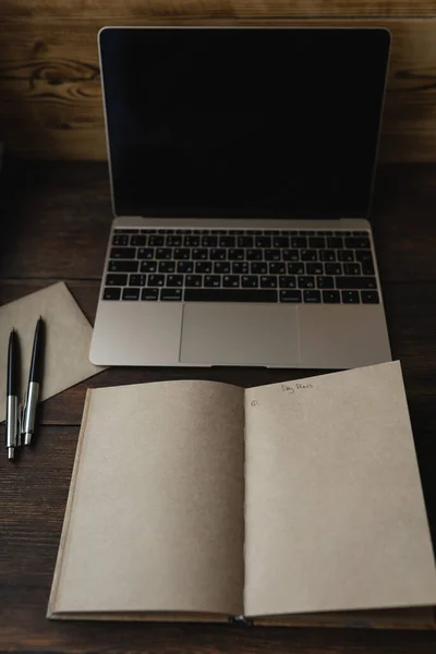 Sözcüklerle dolu bir defter. Dizüstü bilgisayarın yanında bir kalemle Gün planları.