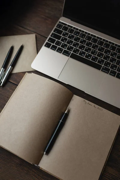 Craft notebook met de woorden Mijn plannen voor 2021 met een pen naast een laptop — Stockfoto