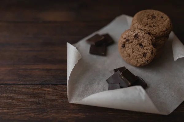 Овсяное печенье и кусочки шоколада на темном деревянном фоне — стоковое фото