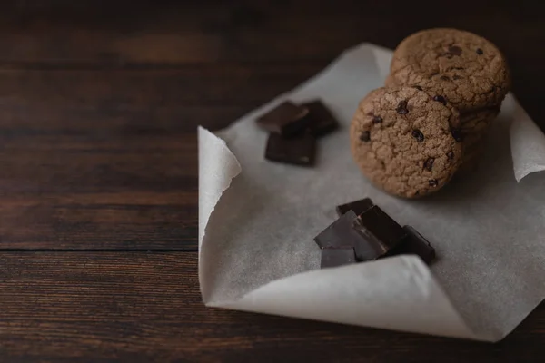 Galletas de avena y trozos de chocolate sobre fondo de madera oscura — Foto de Stock