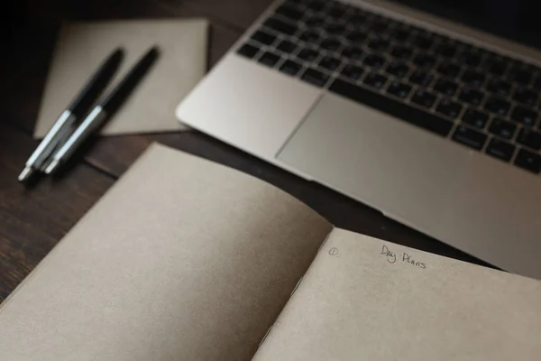 Sözcüklerle dolu bir defter. Dizüstü bilgisayarın yanında bir kalemle Gün planları.