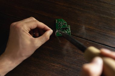 Bir adam bir elektrik panosunu lehim demiriyle tamir eder.