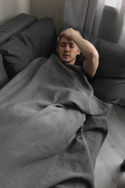A fehér hajú férfi otthon betegeskedik takaróba csomagolva. — Stock Fotó