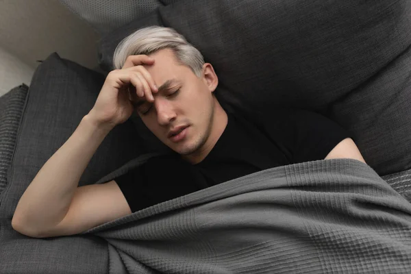 Mannen med vitt hår är sjuk när han ligger på soffan hemma — Stockfoto