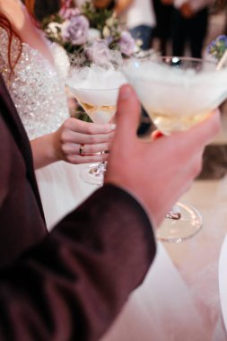 Kadın ve erkek şarap bardaklarını dumanlı içeceklerle tutuyorlar.