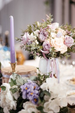 Düğün buketi masanın üstünde, mumların yanında.