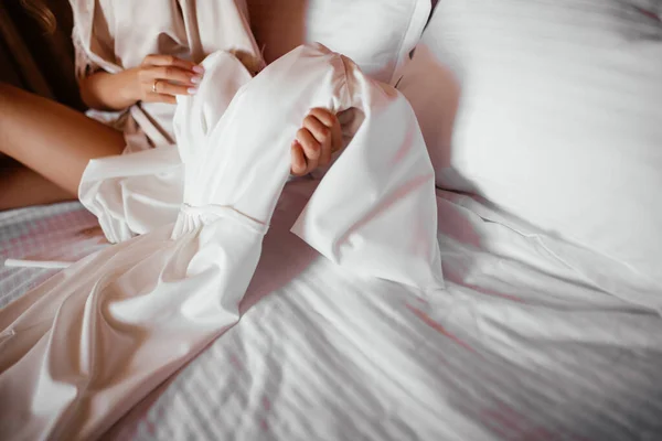 Femme examine robe blanche de mariée assis sur le lit — Photo