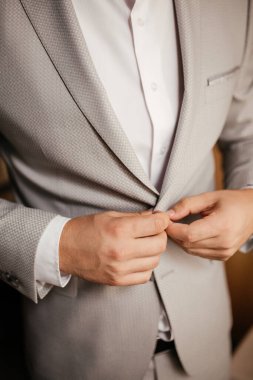 Damat odasında ceketini ilikliyor.
