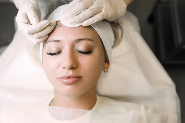 cosmetologist cleans the skin pores of a female patient using a special device