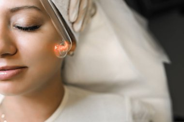 Güzellik uzmanı hastaların derilerini temizlemek için elektrikli bir alet kullanıyor.