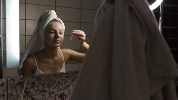 Жінка у ванній після душу наносить сироватку на обличчя піпеткою . — стокове відео