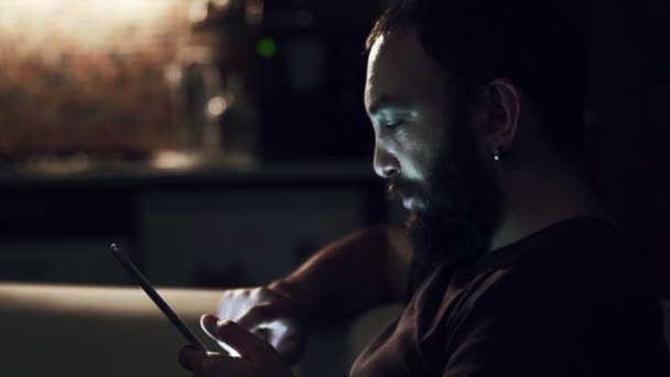 Joven leyendo su tableta en la oscuridad — Vídeo de stock