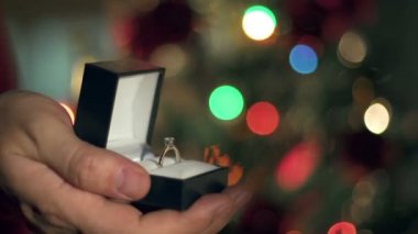 Eller yukarı nişan yüzüğü teklif yakın. Garland yanıp sönüyor. Noel ağacı arka plan