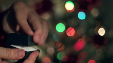 Eller yukarı nişan yüzüğü teklif yakın. Garland yanıp sönüyor. Noel ağacı arka plan