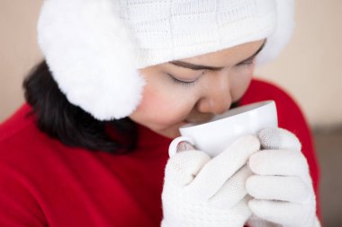 Kırmızı kazak giyen ve Noel gecesi evde kahve içen bir kız.