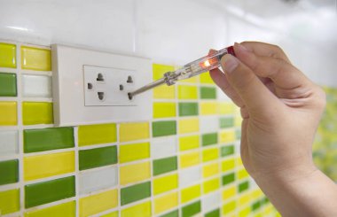 Evin içindeki duvarın arka planında devre ya da voltaj testi yapan bir tornavida.