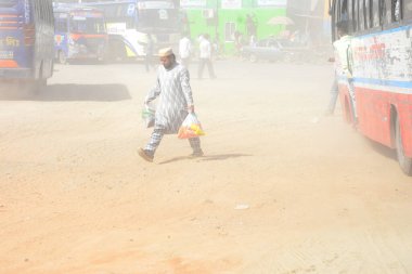 12 Kasım 2020 'de Bangladeş' in Dhaka kentindeki tozlu bir yolda insanlar yürür. Dhaka şehrinin kliması, şehrin pek çok kesimindeki yeni yol inşaatları nedeniyle son iki yıldır endişe verici bir hızla günden güne kötüleşiyor..