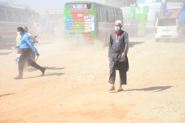 12 Kasım 2020 'de Bangladeş' in Dhaka kentindeki tozlu bir yolda insanlar yürür. Dhaka şehrinin kliması, şehrin pek çok kesimindeki yeni yol inşaatları nedeniyle son iki yıldır endişe verici bir hızla günden güne kötüleşiyor..