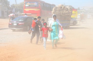 12 Kasım 2020 'de Bangladeş' in Dhaka kentindeki tozlu bir yolda insanlar yürür. Dhaka şehrinin kliması, şehrin pek çok kesimindeki yeni yol inşaatları nedeniyle son iki yıldır endişe verici bir hızla günden güne kötüleşiyor..