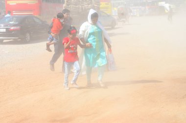 12 Kasım 2020 'de Bangladeş' in Dhaka kentindeki tozlu bir yolda insanlar yürür. Dhaka şehrinin kliması, şehrin pek çok kesimindeki yeni yol inşaatları nedeniyle son iki yıldır endişe verici bir hızla günden güne kötüleşiyor..