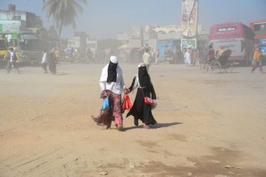 12 Kasım 2020 'de Bangladeş' in Dhaka kentindeki tozlu bir yolda insanlar yürür. Dhaka şehrinin kliması, şehrin pek çok kesimindeki yeni yol inşaatları nedeniyle son iki yıldır endişe verici bir hızla günden güne kötüleşiyor..