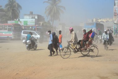 12 Kasım 2020 'de Bangladeş' in Dhaka kentindeki tozlu bir yolda insanlar yürür. Dhaka şehrinin kliması, şehrin pek çok kesimindeki yeni yol inşaatları nedeniyle son iki yıldır endişe verici bir hızla günden güne kötüleşiyor..