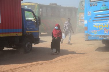 12 Kasım 2020 'de Bangladeş' in Dhaka kentindeki tozlu bir yolda insanlar yürür. Dhaka şehrinin kliması, şehrin pek çok kesimindeki yeni yol inşaatları nedeniyle son iki yıldır endişe verici bir hızla günden güne kötüleşiyor..
